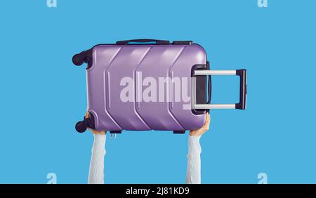 Voyageur tenant une valise à roulettes violet moderne isolée sur fond bleu Banque D'Images
