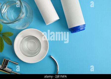 Jeu de filtres à osmose inverse domestiques avec verre et verseuse avec eau purifiée sur une table bleue. Vue de dessus. Composition horizontale. Banque D'Images