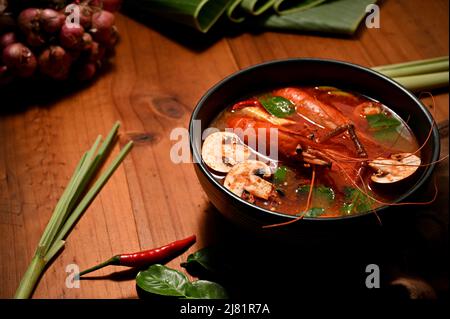 Cuisine thaïlandaise, Tom Yam Kung dans un bol noir ou soupe thaïlandaise épicée à la noix de coco avec crevettes sur une table en bois. Banque D'Images