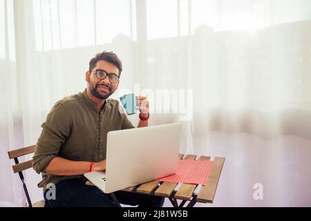 Homme d'affaires asiatique indépendant travaillant avec un ordinateur portable et de boire du café de la coupe bleue à la véranda balcony.freelance et travail à distance Banque D'Images