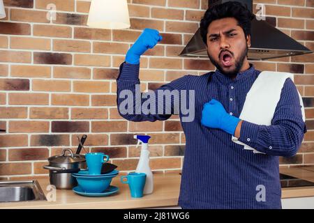 L'homme africain nettoyant la hotte de la cuisinière à la maison, mur de brique avec une montagne de plats sales non lavés près de l'arrière-plan de l'évier Banque D'Images