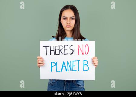 Une jeune fille militante environnementale sérieuse tenant une bannière avec il n'y a pas de texte de la planète B contre un fond vert Banque D'Images