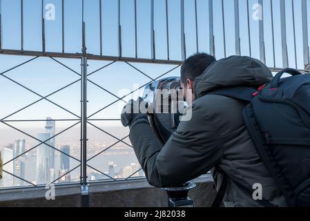 Gros plan d'un garçon qui ressemble à manhattan à travers un télescope, de l'Empire State Building Banque D'Images