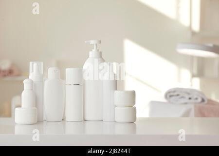 Bouteilles et bocaux blancs avec produits de soin de la peau placés sur une table dans un salon de beauté Banque D'Images