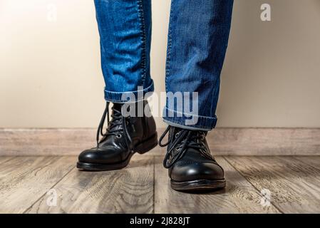 Homme en cuir noir bottes et jeans sur un plancher en bois Banque D'Images