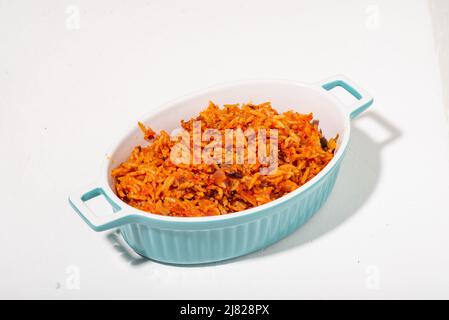 Le riz Jollof dans un plat sur fond blanc. Nourriture traditionnelle nigériane à base de riz, de tomates et d'épices. Banque D'Images