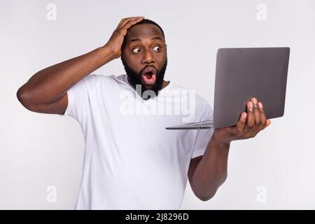 Photo de choqué funky Guy habillé décontracté t-shirt bras tête regardant moderne gadget isolé couleur blanc fond Banque D'Images