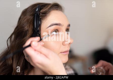 Maquilleuse application de l'ombre oculaire à la paupière inférieure d'une fille avec un pinceau. Photo de haute qualité Banque D'Images