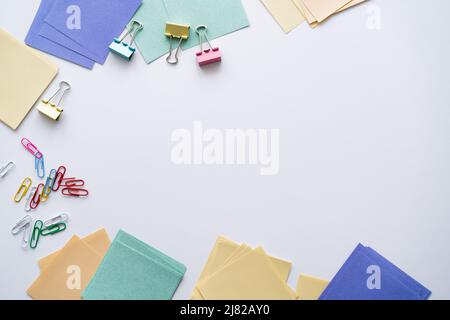 vue de dessus des clips de pliage arrière colorés et des notes de papier sur le blanc Banque D'Images