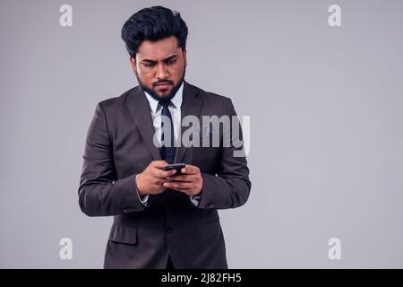 Succès beau homme d'affaires arabe costume classique parlant par téléphone dans fond blanc de studio Banque D'Images