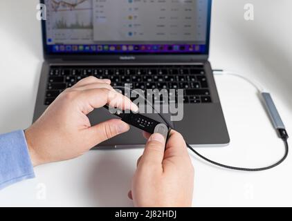 Russie, Krasnodar - 15 avril 2022: Homme utilisant le matériel crypto-monnaie Ledger. Solution de stockage sûre pour bitcoin. Banque D'Images