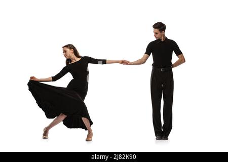 Portrait dynamique de jeunes danseurs émotifs vêtus de tenues noires dansant danse de salle de bal isolée sur fond blanc. Concept d'art, beauté, musique, style. Banque D'Images