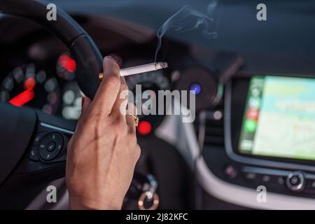 11 mai 2022, Schleswig-Holstein, Flensburg: Une femme est assise derrière le volant de sa voiture avec une cigarette allumée. Photo: Axel Heimken/dpa Banque D'Images