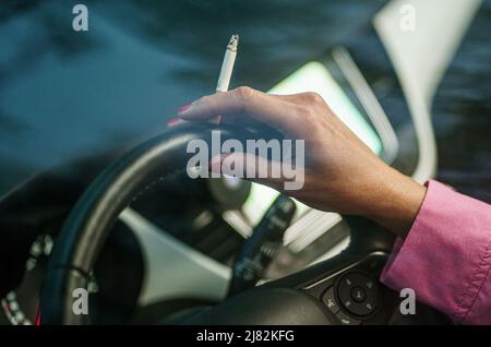 11 mai 2022, Schleswig-Holstein, Flensburg: Une femme est assise derrière le volant de sa voiture avec une cigarette allumée. Photo: Axel Heimken/dpa Banque D'Images