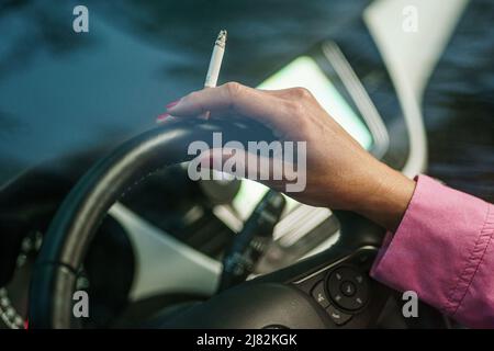 11 mai 2022, Schleswig-Holstein, Flensburg: Une femme est assise derrière le volant de sa voiture avec une cigarette allumée. Photo: Axel Heimken/dpa Banque D'Images