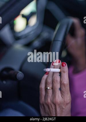 11 mai 2022, Schleswig-Holstein, Flensburg: Une femme est assise derrière le volant de sa voiture avec une cigarette allumée. Photo: Axel Heimken/dpa Banque D'Images