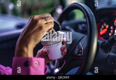 11 mai 2022, Schleswig-Holstein, Flensburg: Une femme vole une cigarette dans un cendrier derrière la roue de sa voiture. Photo: Axel Heimken/dpa Banque D'Images