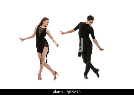 QuickStep. Portrait dynamique de jeunes danseurs émotifs vêtus de tenues noires dansant danse de salle de bal isolée sur fond blanc. Concept d'art, beauté Banque D'Images