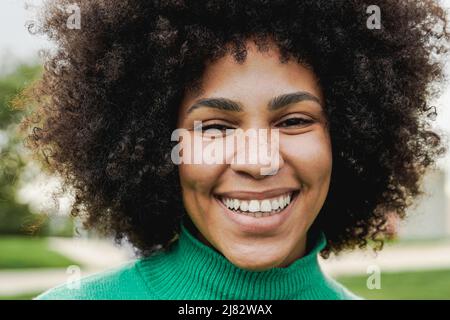 Jeune fille hispanique souriant et regardant l'appareil photo à l'extérieur dans le parc de la ville - Focus sur le visage Banque D'Images