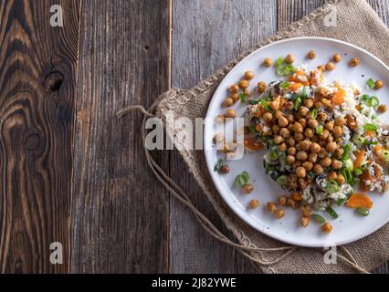 Dîner ou déjeuner végétalien avec pois chiches rôtis et riz aux légumes sur une assiette isolée sur une table en bois. Vue de dessus avec espace de copie Banque D'Images