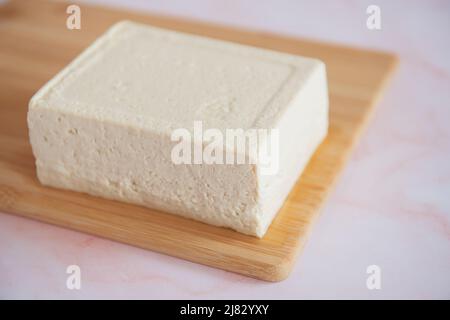Bloc de tofu sur une planche à découper Banque D'Images