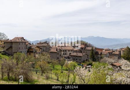 Le village rural idyllique de Campolo dans les Apennines au printemps. Arbres fruitiers en fleur, neige dans la montagne Corno Alle Scale. Banque D'Images