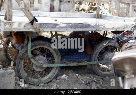 Hyderabad (Pakistan), 12 mai 2022. Vendeur de rue prenant le repos sous la poussette pour le garder à l'économie de coups de vagues de chaleur pendant une journée chaude de la saison d'été, près de Shafiq Mor région de Karachi le jeudi, 12 mai 2022. Banque D'Images