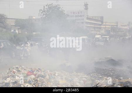 Hyderabad (Pakistan), 12 mai 2022. Forte fumée sombre augmentant les ordures ménagères causant des problèmes aux navetteurs lors du déplacement sur la route Rashid Minhas à Karachi le jeudi 12 mai 2022. Banque D'Images