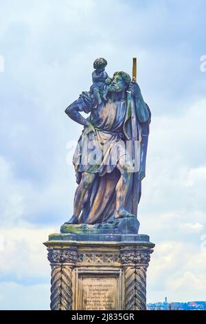 La sculpture en pierre historique de St Christopher décore le pont Charles de l'autre côté de la Vltava, Prague, République tchèque Banque D'Images