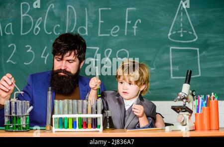 Programme scolaire. Garçon d'école mignon enfant expérimentant avec des liquides. La persévérance paye. Tubes à essai pour enseignants et enfants. Leçon scolaire Banque D'Images