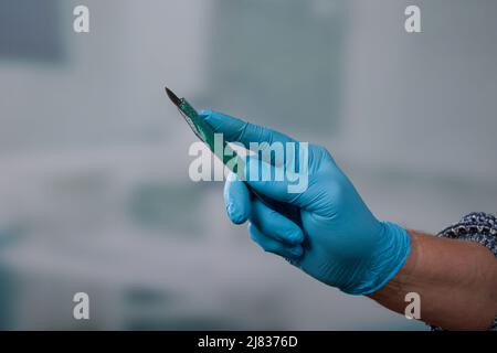 Main du médecin avec un nouveau scalpel jetable devant une salle de clinique Banque D'Images