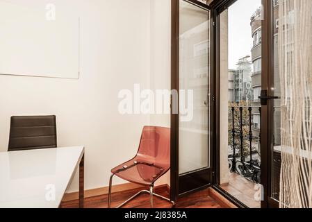 Coin d'un bureau avec chaises en méthacrylate et cuir noir avec une porte de balcon avec vue ouverte Banque D'Images