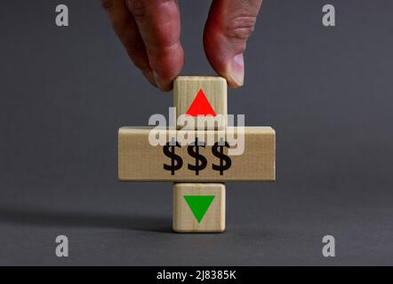 Symbole taux en dollars. Homme d'affaires tient un cube en bois avec une flèche symbolisant que les taux du dollar vont à la baisse ou à la hausse. Magnifique fond gris de table gris Banque D'Images