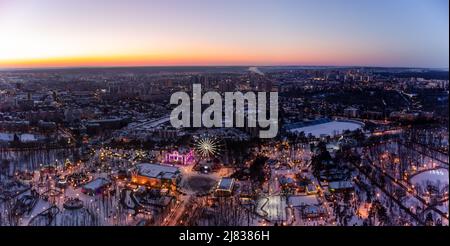 Vue panoramique aérienne sur les lumières de la ville, grande roue, animations en hiver, couvertes de neige blanche. Centre-ville de Kharkiv dans les couleurs du coucher du soleil, divertissement Go Banque D'Images