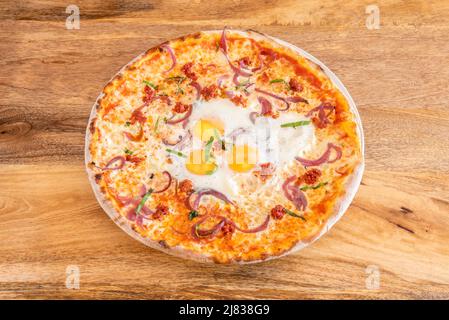 Grande pizza avec légumes, oignons, tomates déshydratées et trois oeufs frits avec des lanières de poivre vert Banque D'Images