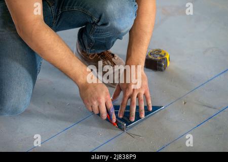 Travailleur de la construction mesurant et décrivant le plancher d'une unité de complexe d'appartements de logement abordable Banque D'Images