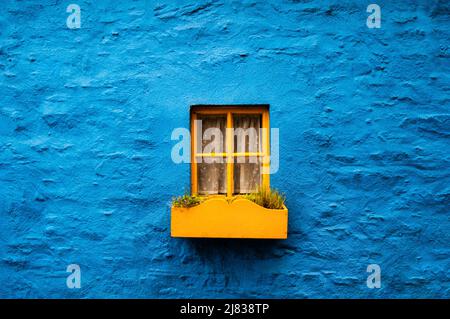 Fenêtre jaune contre un mur bleu à Kinsale, Irlande. Banque D'Images