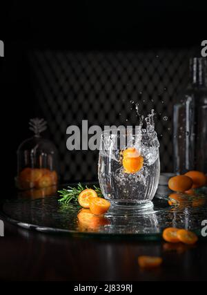 Cocktail alcoolisé avec une petite éclaboussure sur fond sombre. Boisson gazeuse rafraîchissante aux agrumes dans un verre transparent. Banque D'Images