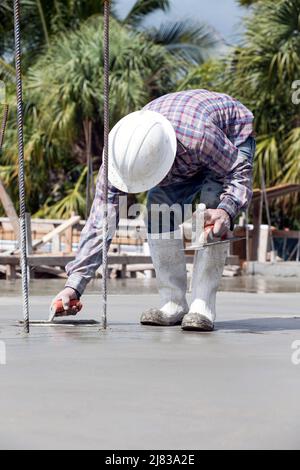 Ouvrier de construction lissant le béton fraîchement coulé avec une truelle Banque D'Images