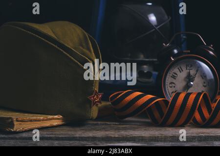 Soldats russes Cap, St. George ruban, vieux livre et un réveil avec lampe au kérosène. Le jour de la victoire est le 9th mai Banque D'Images