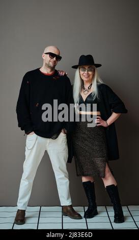 Portrait en studio vertical complet d'un homme et d'une femme à la mode, mûrs et vêtu de vêtements de goth modernes posé sur l'appareil photo Banque D'Images