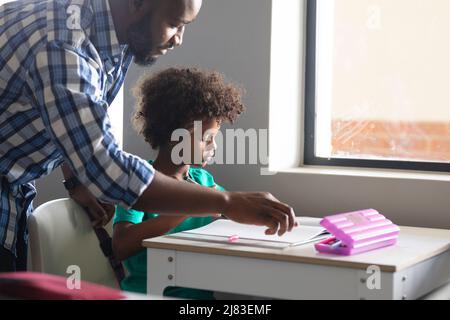 Jeune enseignant afro-américain enseignant à l'école élémentaire afro-américaine assis à son bureau Banque D'Images