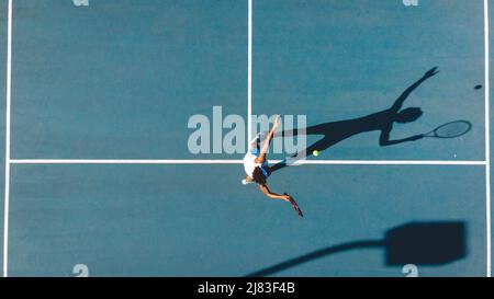 Vue en hauteur d'une jeune femme afro-américaine servant sur un court de tennis bleu par beau temps Banque D'Images