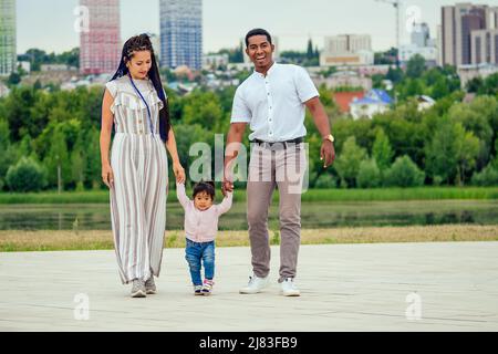 mère et père transnationaux interraciaux marchant avec leur petite fille de race mixte dans le parc d'automne Banque D'Images