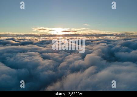 Vue aérienne d'en haut à haute altitude de nuages de cumulus bouffis denses volant en soirée. Coucher de soleil incroyable du point de vue de la fenêtre de l'avion Banque D'Images