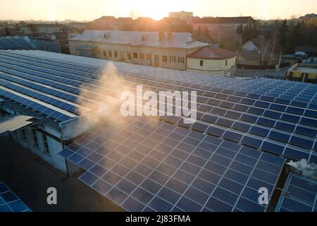 Vue aérienne des panneaux solaires photovoltaïques bleus montés sur le toit d'un bâtiment industriel pour produire de l'électricité écologique verte. Production de Banque D'Images