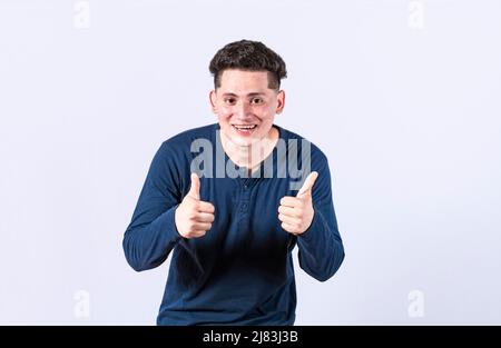 Positif gars avec les pouces vers le haut faire ok, jeune homme avec les pouces vers le haut sur fond blanc, homme souriant montrant le geste ok regardant l'appareil photo Banque D'Images