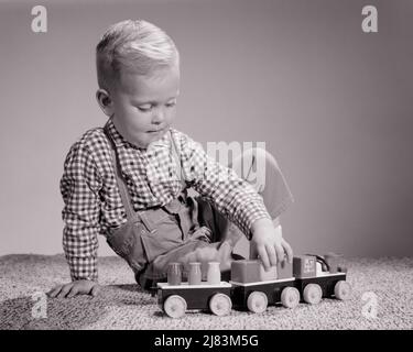 1960S BLONDE ENFANT GARÇON JOUANT AVEC LE PLASTIQUE JOUET TRAIN - J11566 HAR001 HARS MAISON VIE COPIE ESPACE DEMI-LONGUEUR COMBINAISONS MÂLES B&W BONHEUR GAI FIERTÉ SOURIANTE CONCEPTUEL IMAGINATION JOYEUX BÉBÉ GARÇON ÉLÉGANT JEUNES NOIR ET BLANC CAUCASIEN ETHNIE HAR001 OLD FASHIONED Banque D'Images