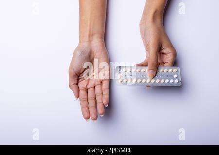 Les mains cultivées d'une femme afro-américaine de taille moyenne, tenant des médicaments sur fond blanc, espace de copie Banque D'Images