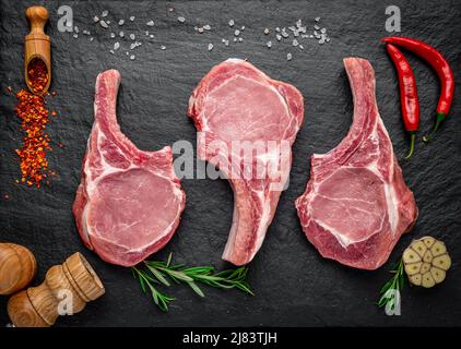 Steak de porc frais et cru aux épices sur fond sombre. Viande fraîche Banque D'Images